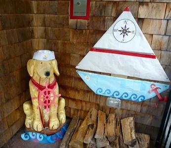 Dog statue in a sailor hat beside a sailboat decoration